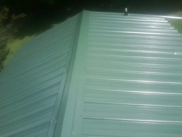 New green metal panels meeting at the ridge of a roof — Flat Roof Repair work by our crew in Felt