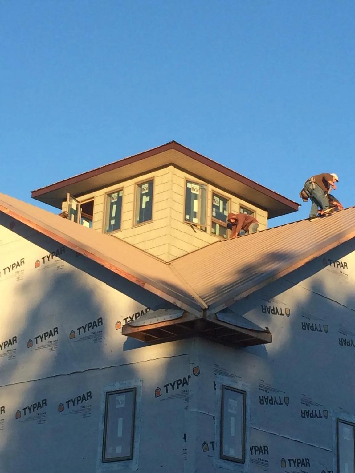 Roofers working around a rooftop cupola on a new metal roof at sunset — Roof Waterproofing in Felt by Roofing Brothers